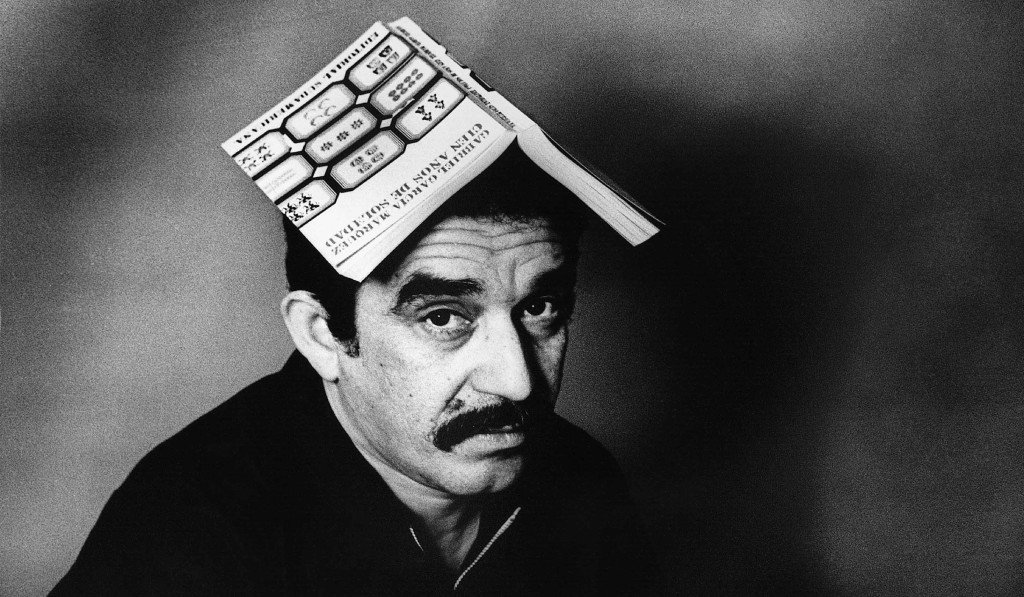 1975, Colombia --- Nobel-prize winning author Gabriel Garcia Marquez sits with a copy on his book One Hundred Years of Solitude) open on his head. --- Image by © Colita/CORBIS